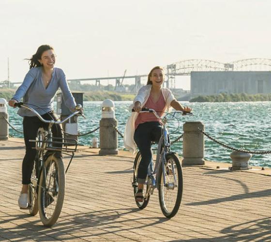 Two students on bicycles riding along the waterfront boardwalk