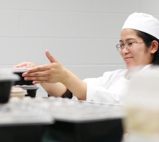 Culinary student preparing takeout containers for Gourmet 2 Go