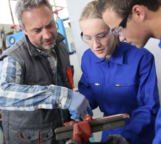 Students listening and working with plumbing instructor