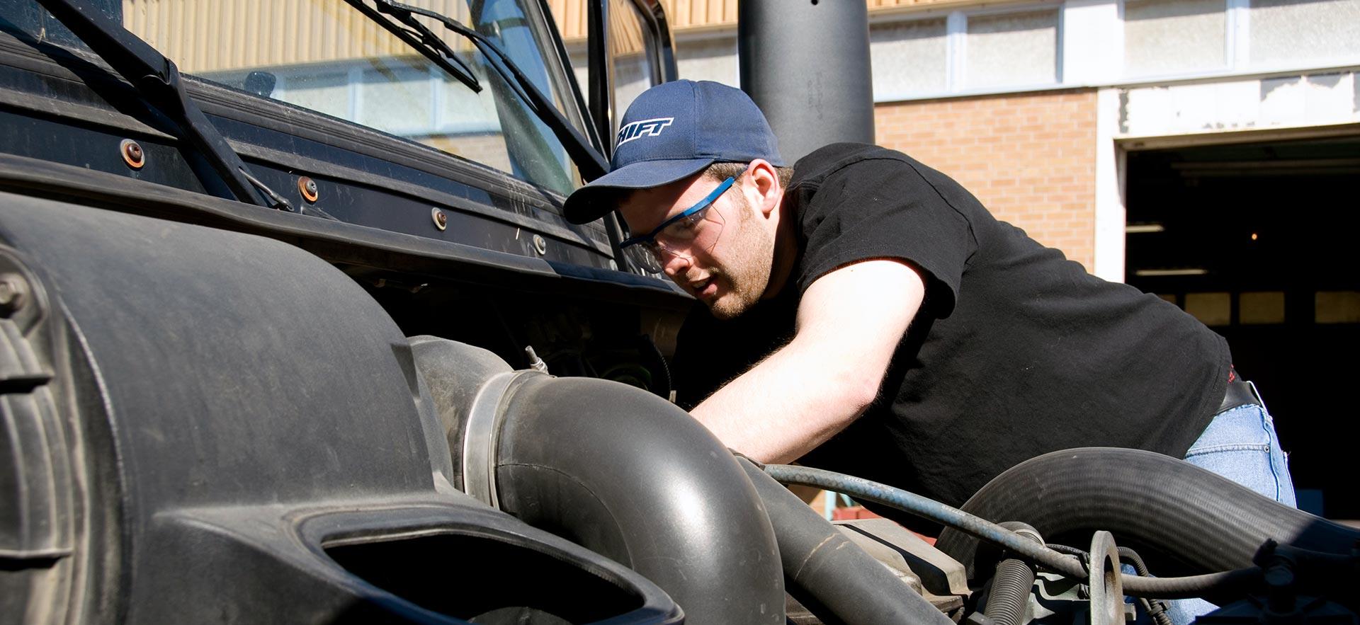 One male Truck and Coach Technician student works on a truck coach engine. 