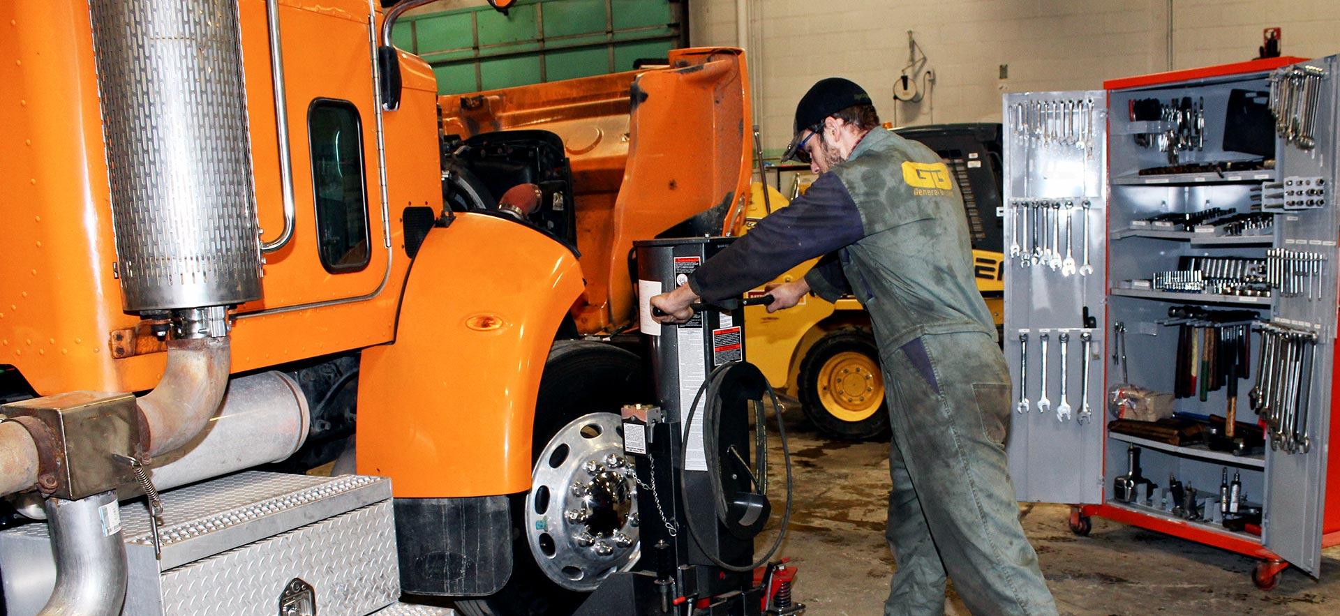 One male Heavy Duty Equipment Technician student stands outside grading truck. 