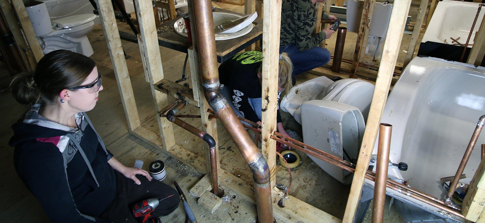 Female plumbing students work on in-class plumbing assignment as Sault College. 