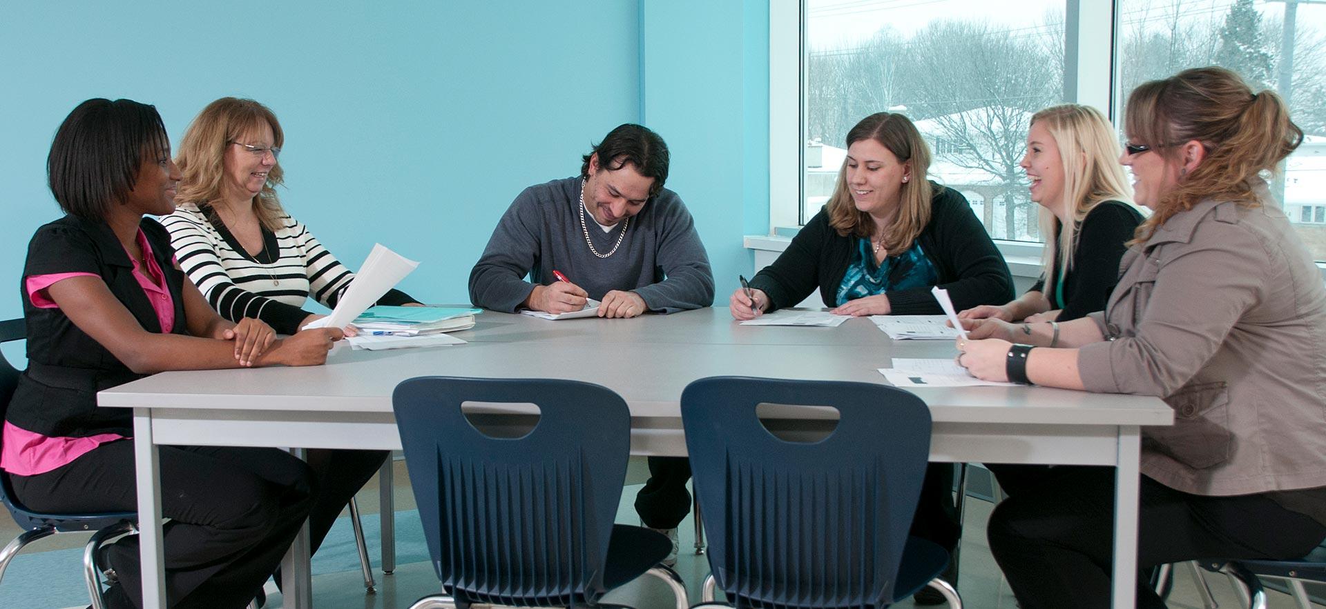 A group of Project Management students discuss an in-class assignment with their instructor. 