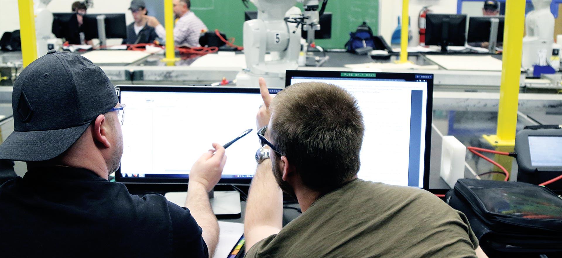 Two male Electrical Engineering Technology - Process Automation students fine tuning an automation program.                         