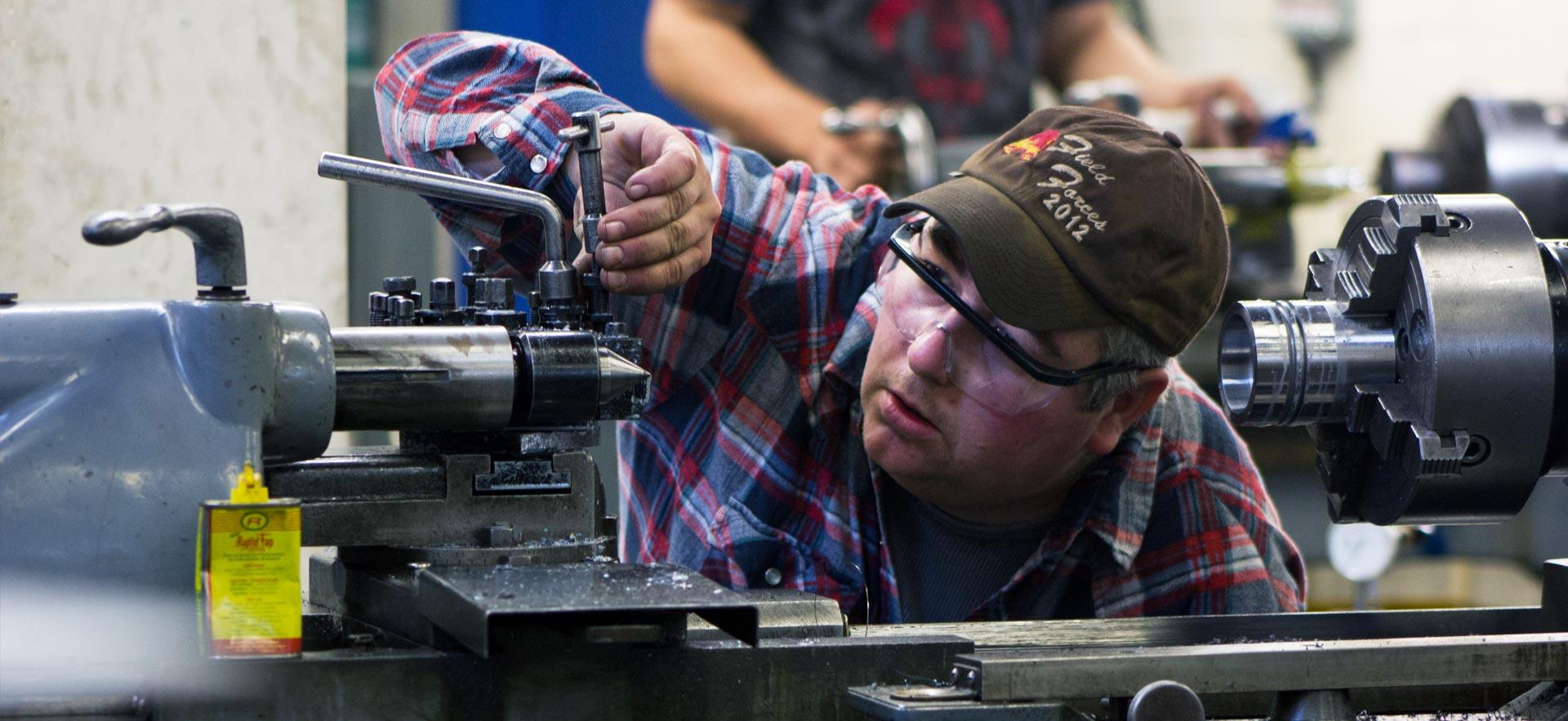 Male Mechanical Engineering Technician - Manufacturing student makes some careful adjustments. 