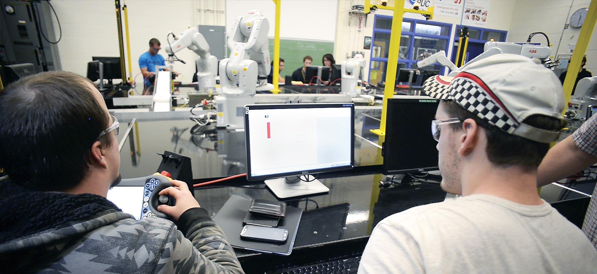 Two male Robotics and Automation students work on their automated class project. 