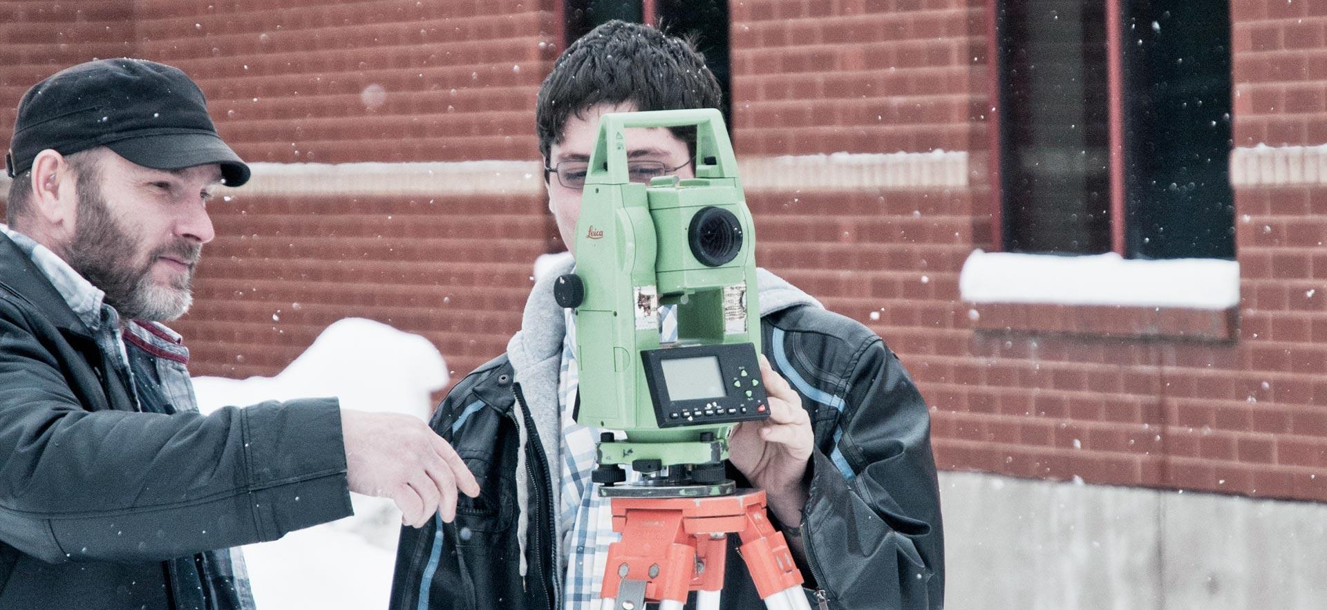 Two male Civil Engineering Technician students practice surveying outside the Sault College campus..