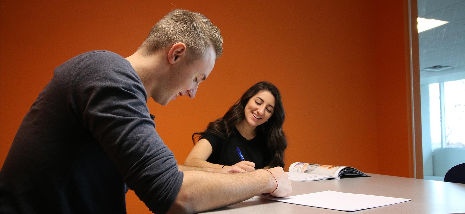 One male and one female General Arts and Science - One-Year students do homework together in a study area. 