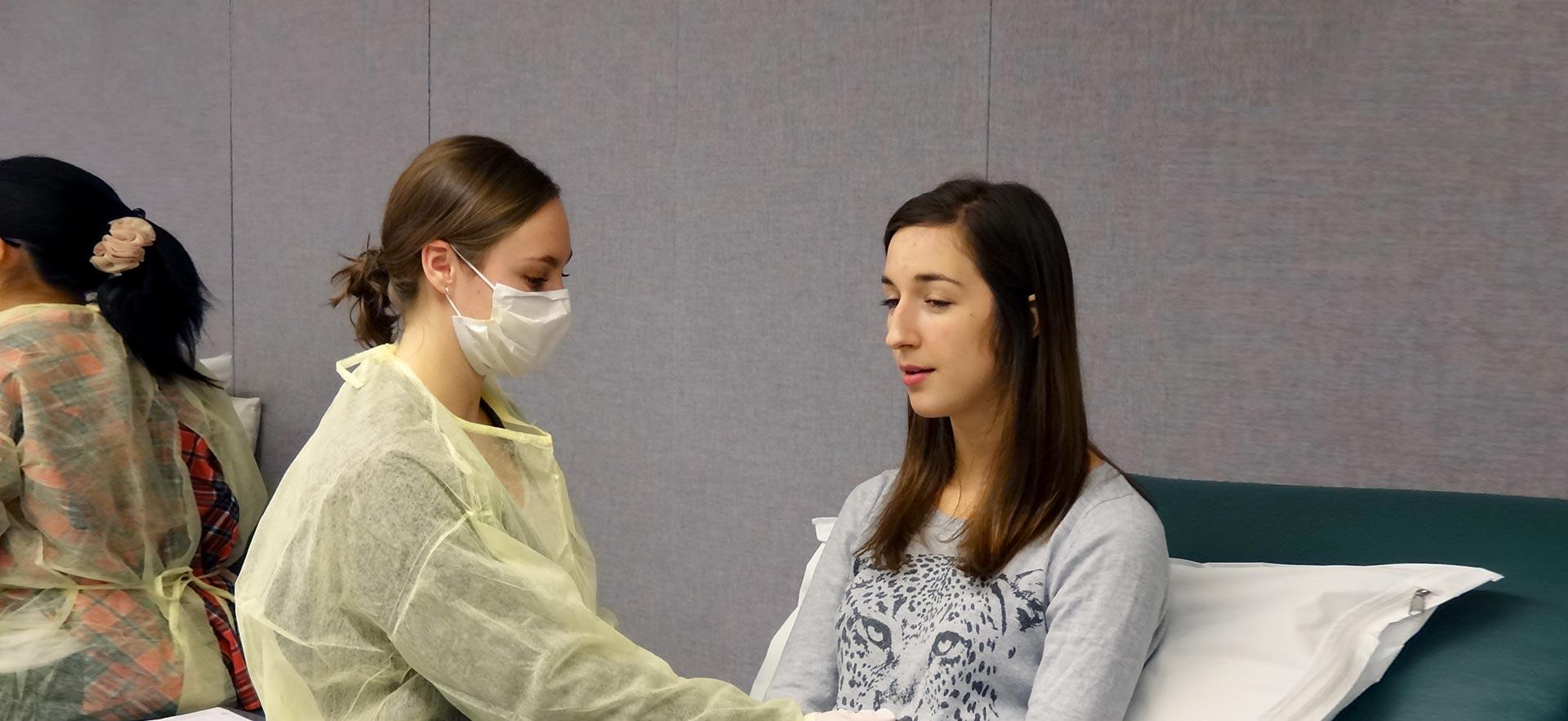 Physiotherapy student helping another female student.