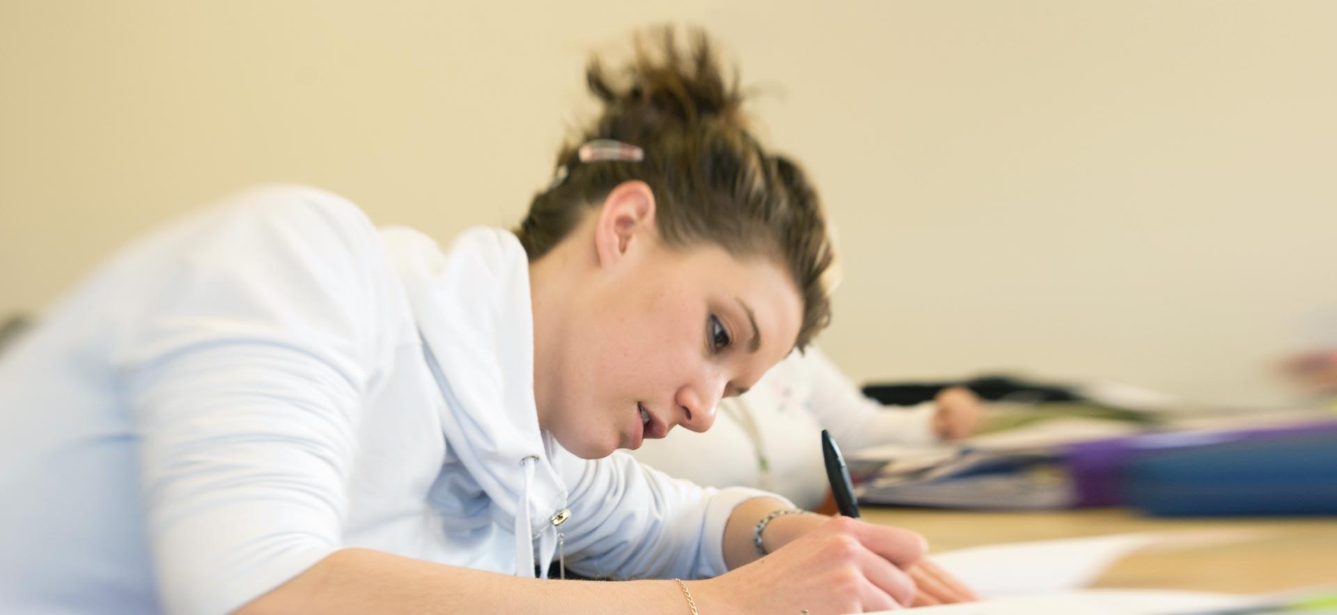 A female Pre-Health Sciences Pathway to Certificates and Diplomas student works on an in-class assignment. 