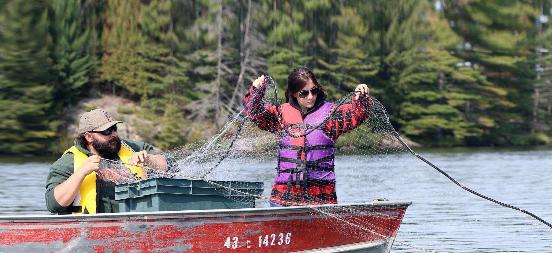 A female Fish and Wildlife Conservation Technician student sets a net froma boat to retrieve samples. 