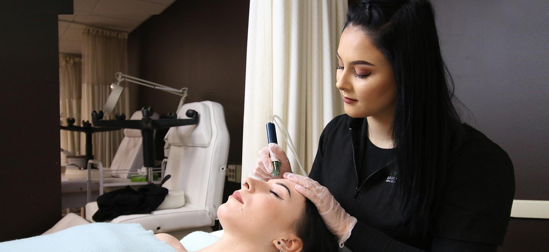 One female Esthetician student applies a skin treatment to another student in the Sault College salon spa.