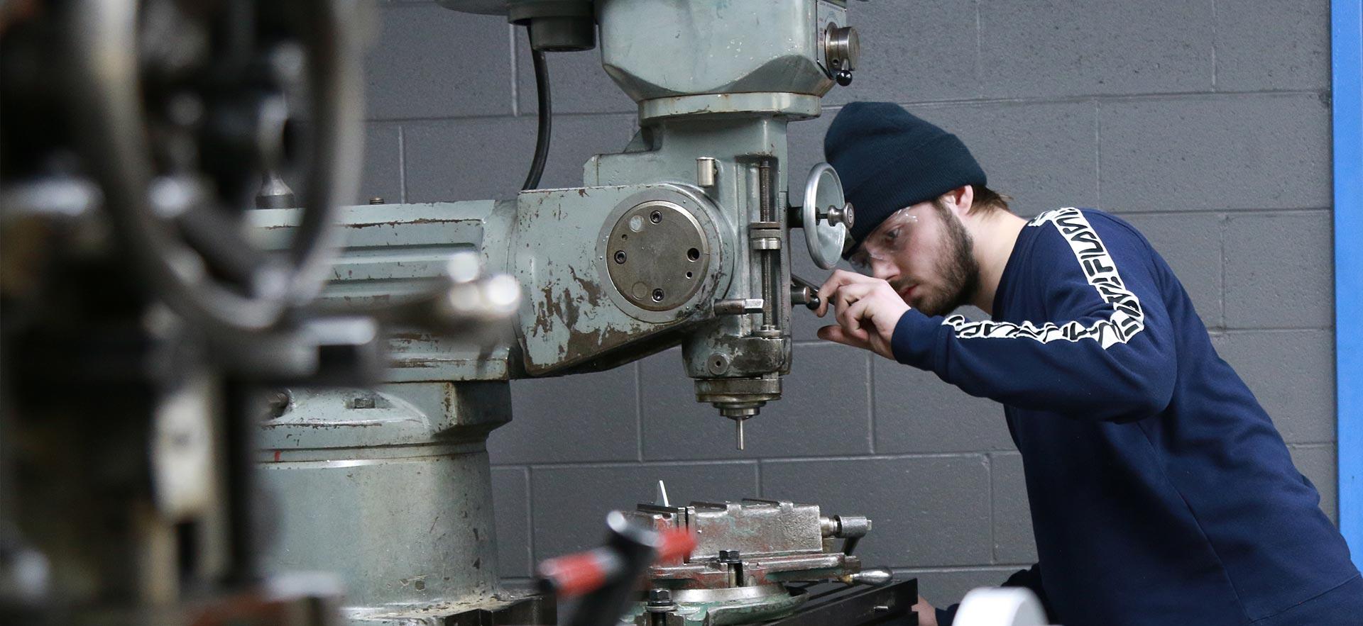 A male  Mechanical Techniques - Industrial Maintenance (Millwright) student makes some adjustments at his drill press. 