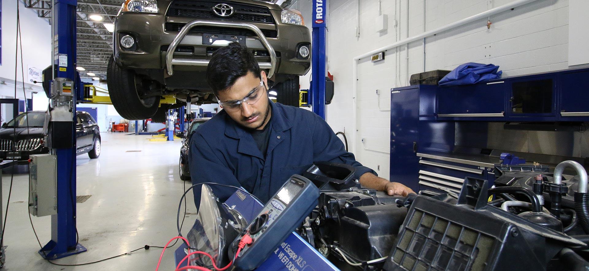 One male Motive Power Technician - Advanced Repair student runs diagnostics on a car engine.