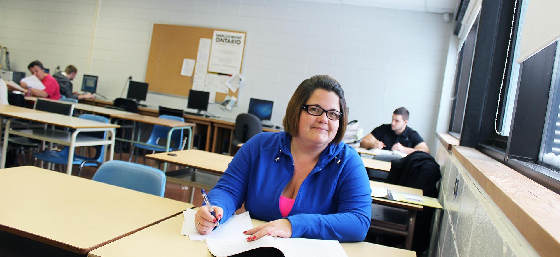 Female Academic Upgrading Academic and Career Entrance (ACE) student sitting at her desk in class. 