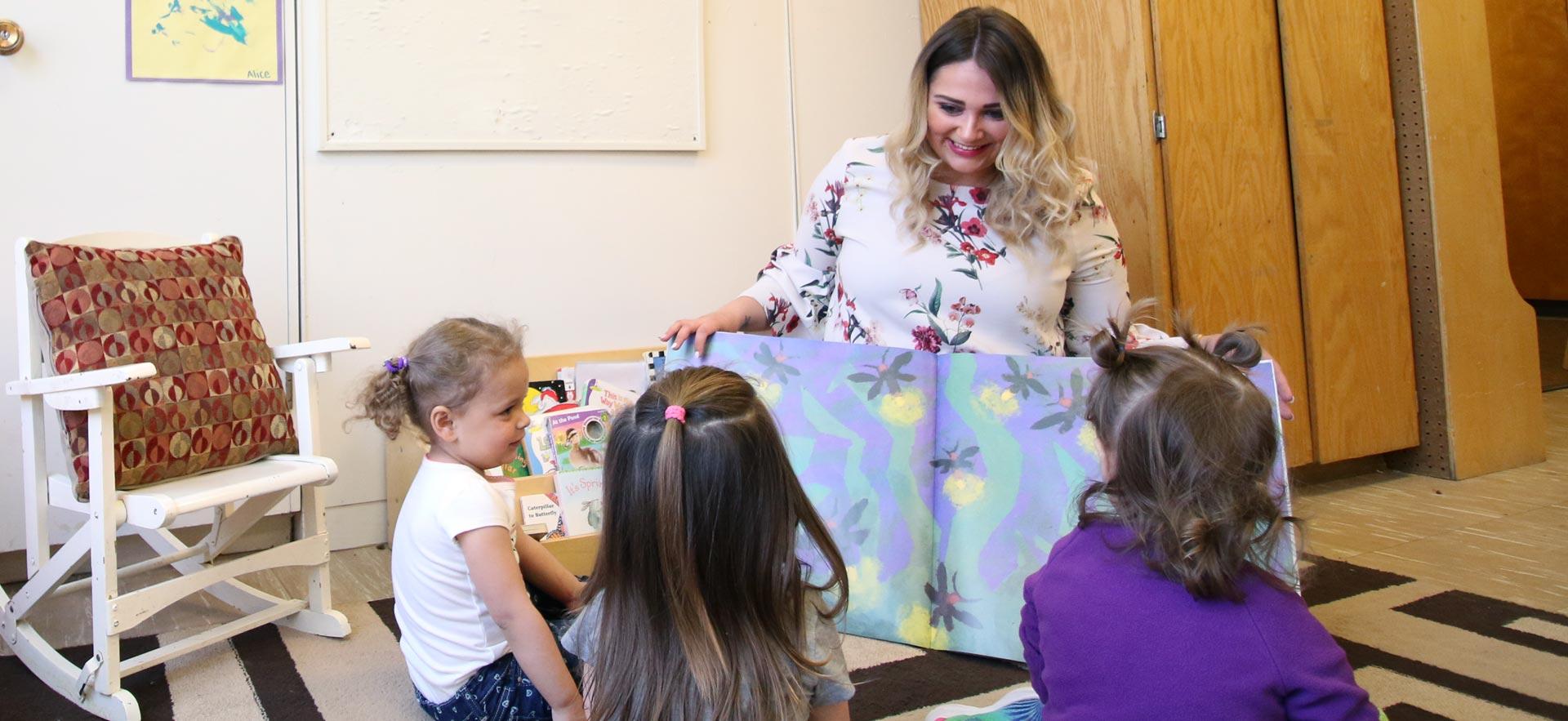 Female early childhood education student reads to young children.