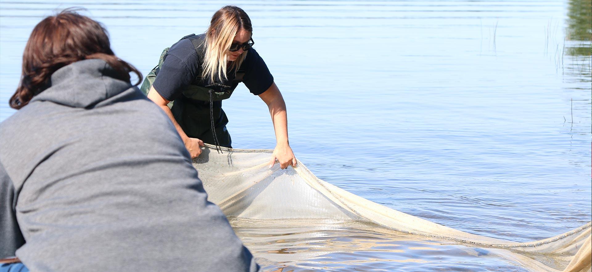 Two female Fish and wildlife students set a net.
