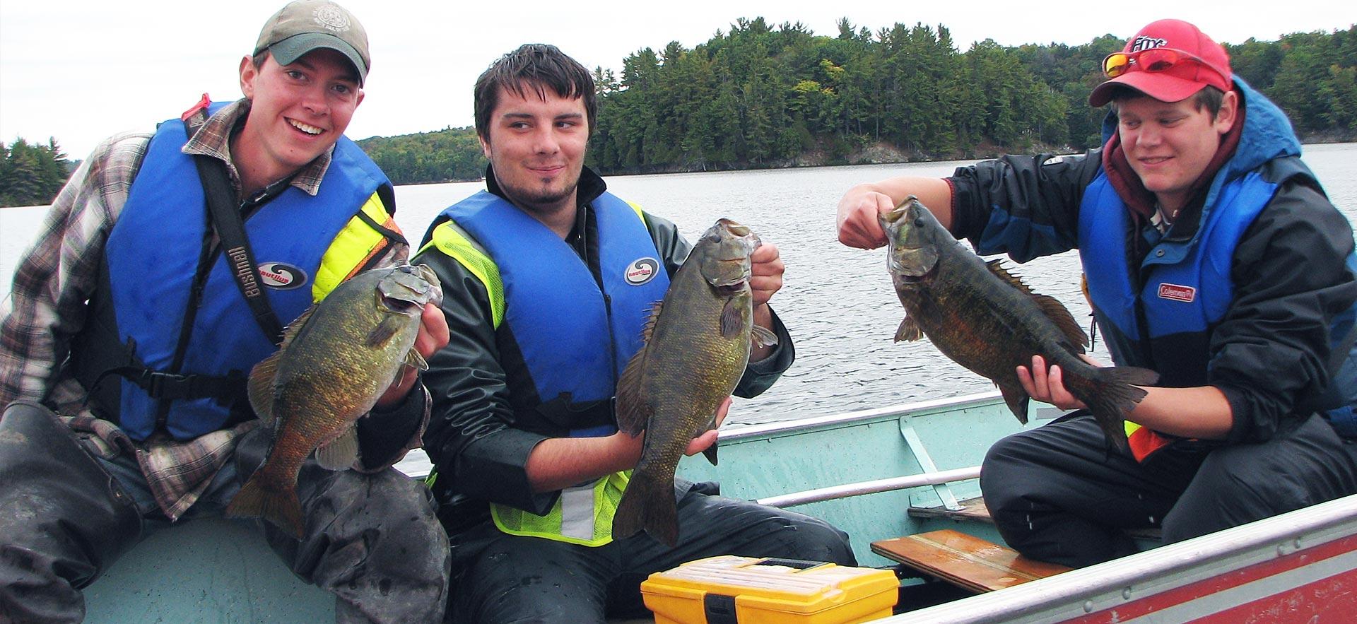 Male Fish and Wildlife students holdup fish they caught.