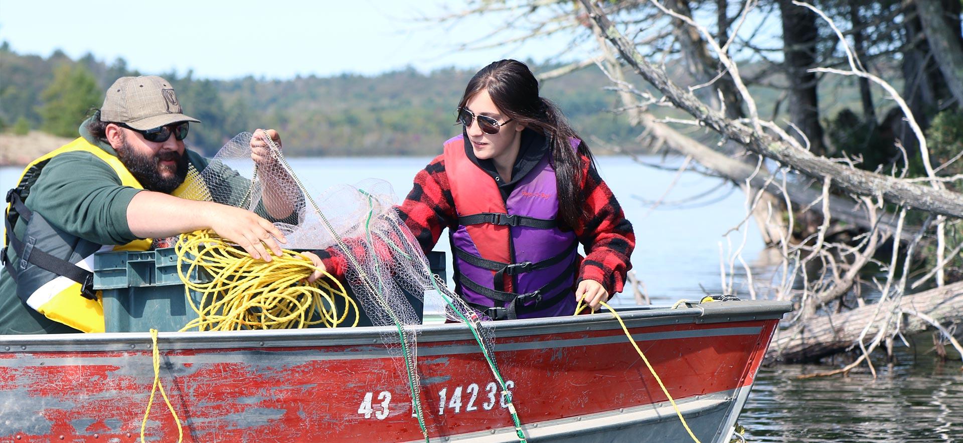 Two Fish and Wildlife students set a new in the water from a boat.