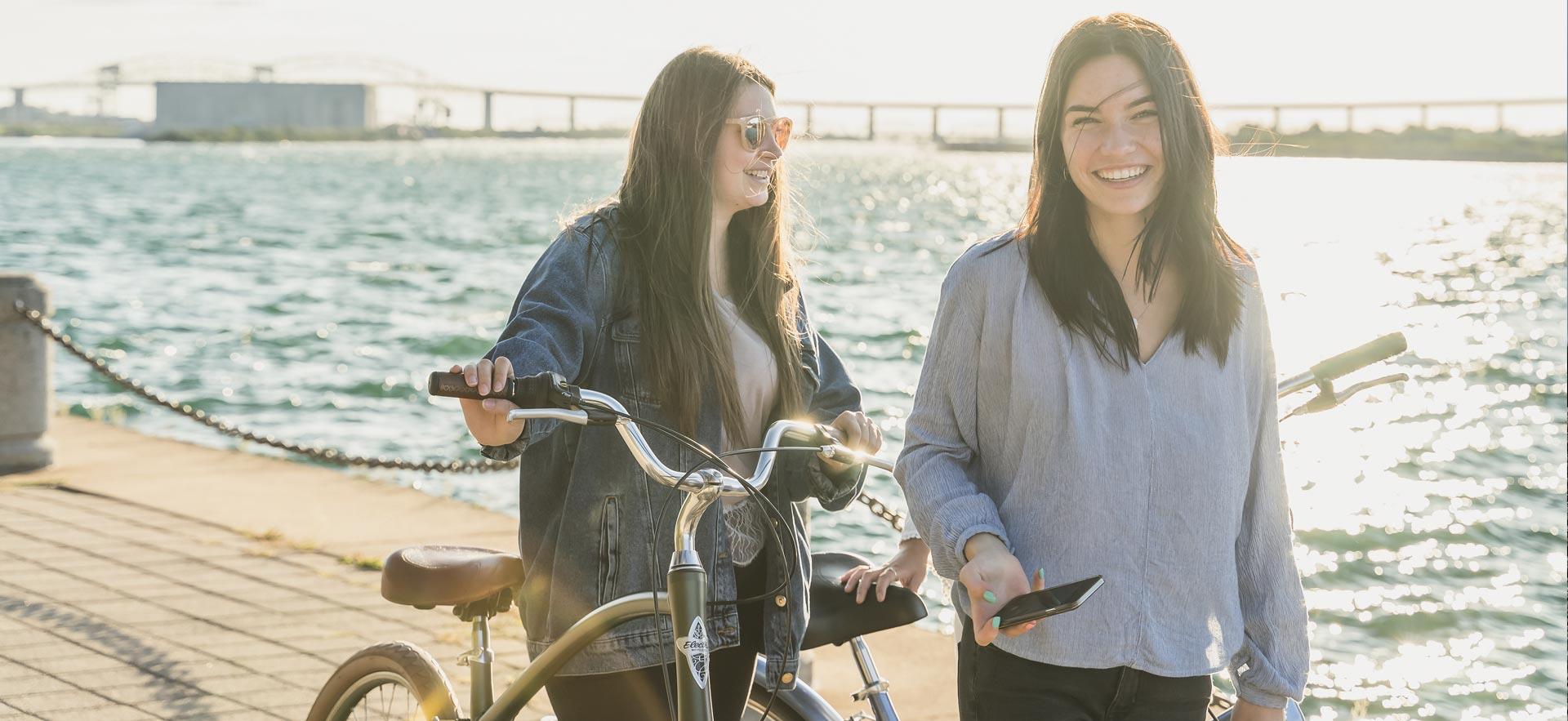 Two young women walking and smiling on boardwalk.