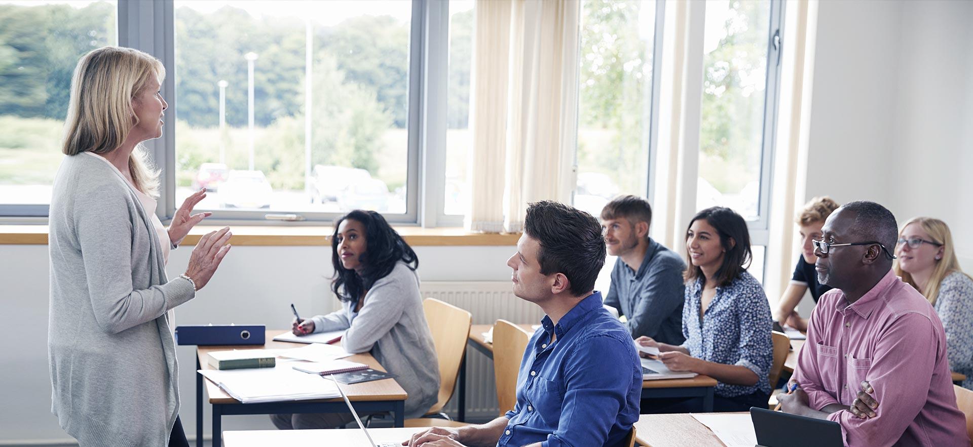 Female teaching adults in class room.