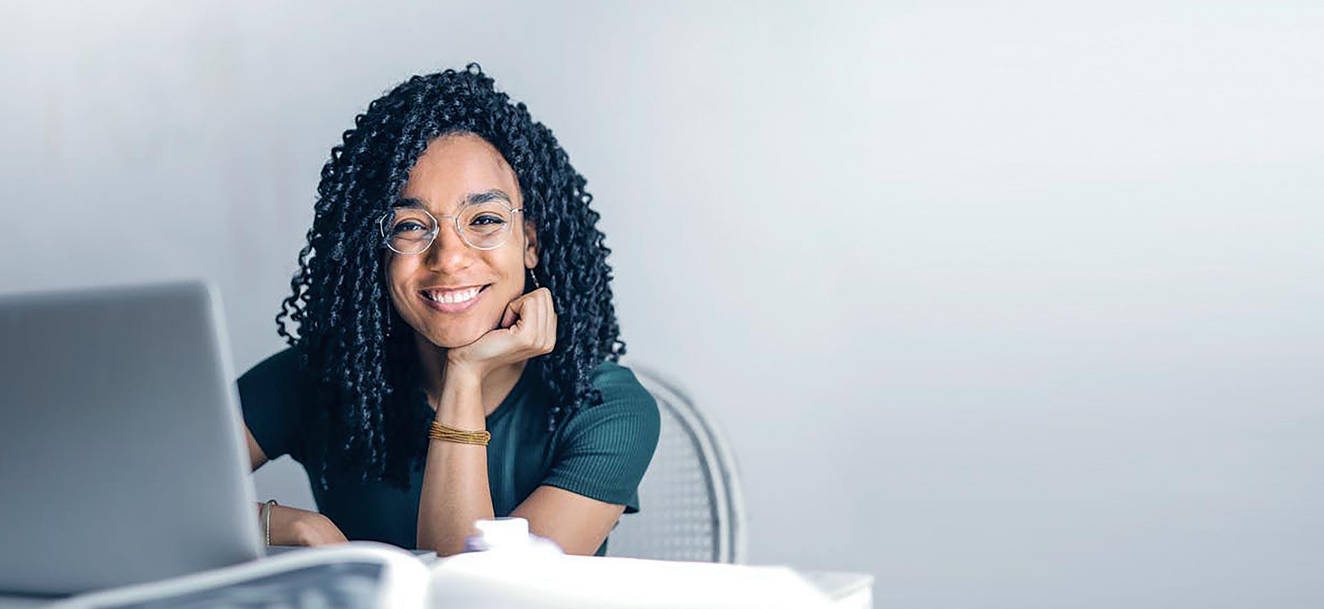 Woman smiling at her desk next to her computer.