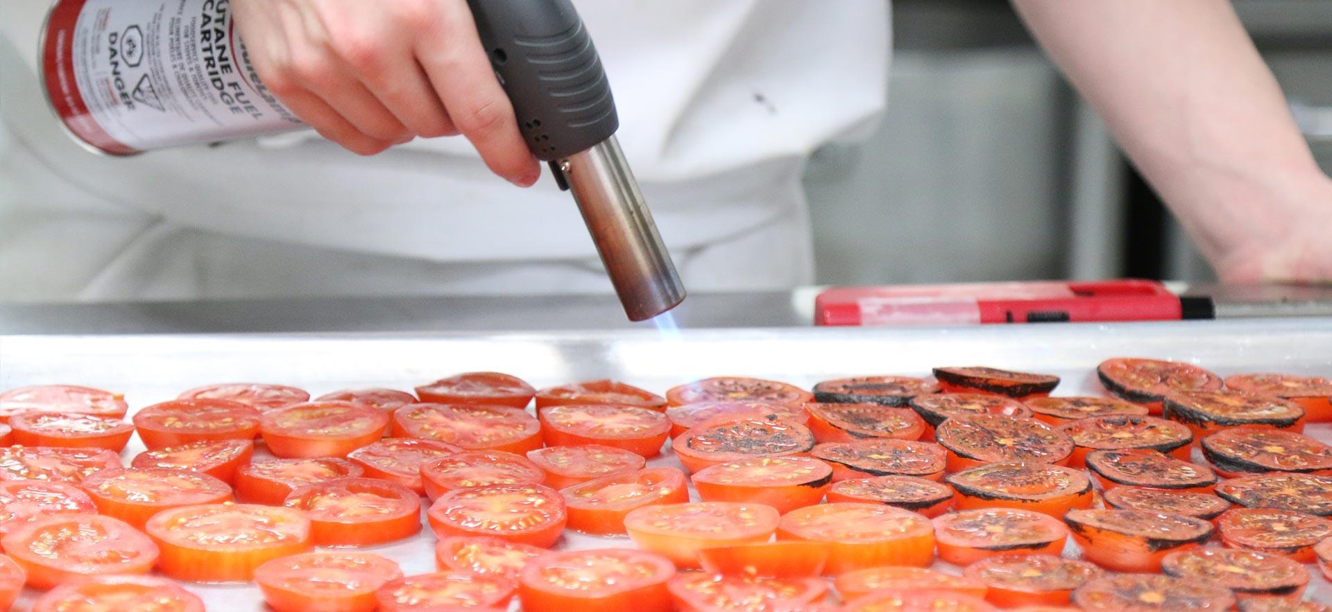 A culinary student fire roasting tomatoes in one the Sault College culinary kitchens.