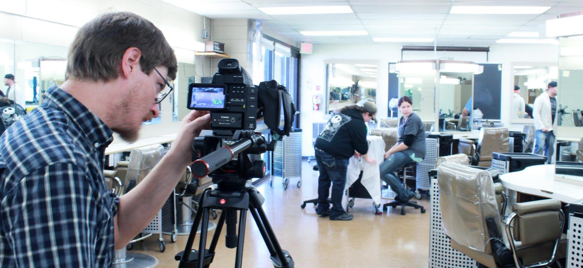 Male digital video student shoots video in the Sault College hairstyling salon.