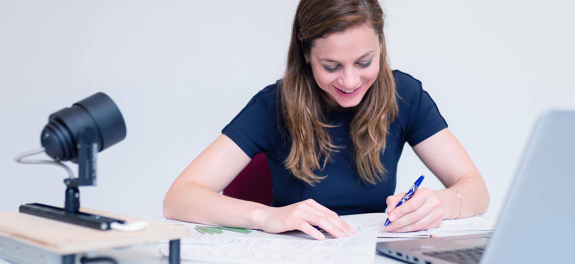 A female business writer smiles as she works on a project.