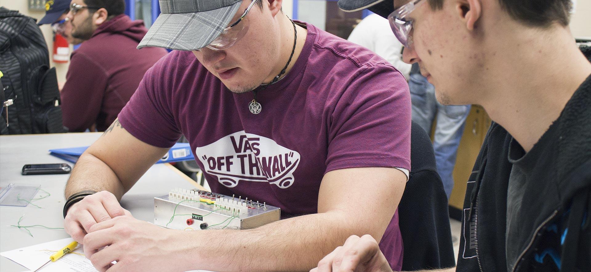 Two male Electrical Engineering students work on a class project.