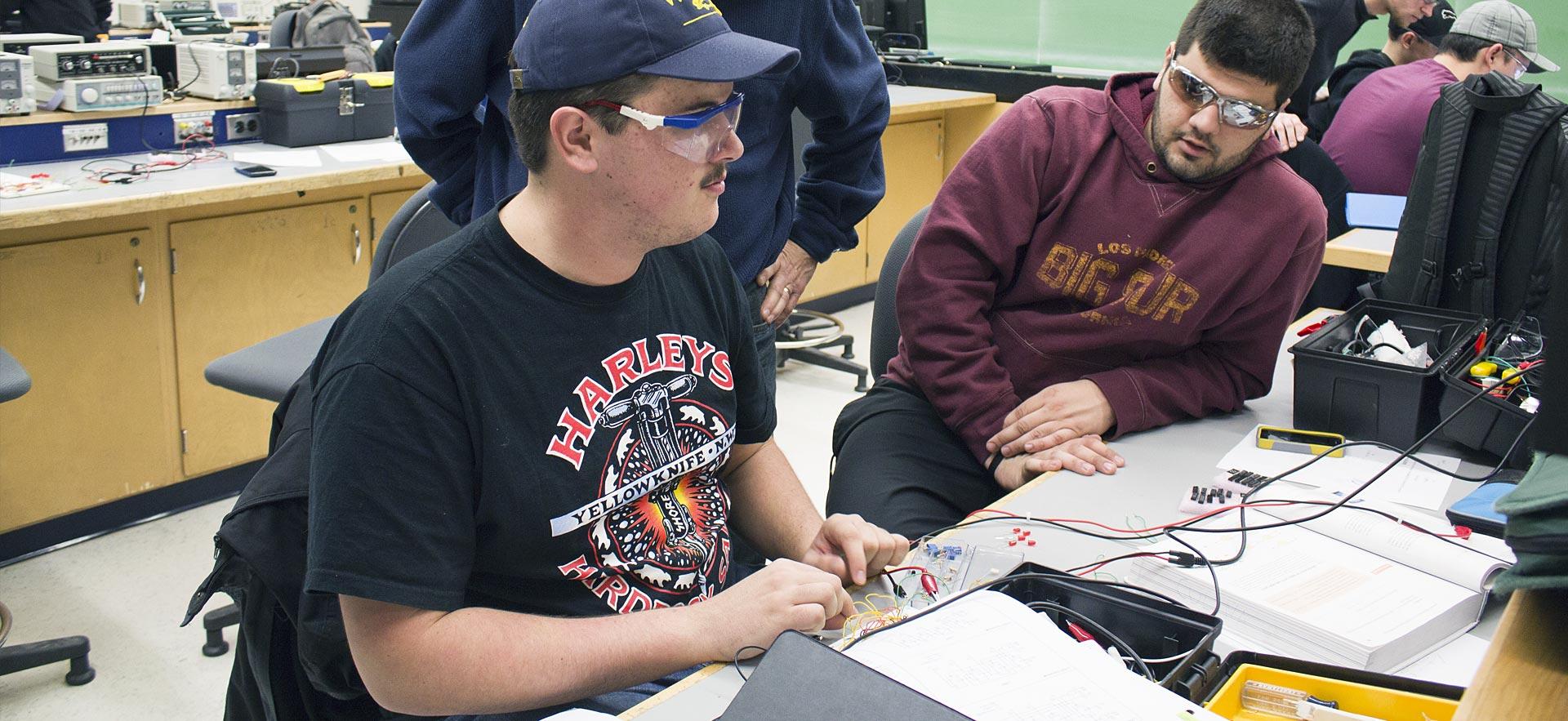 Two male Electrical Engineering students work on a class project.
