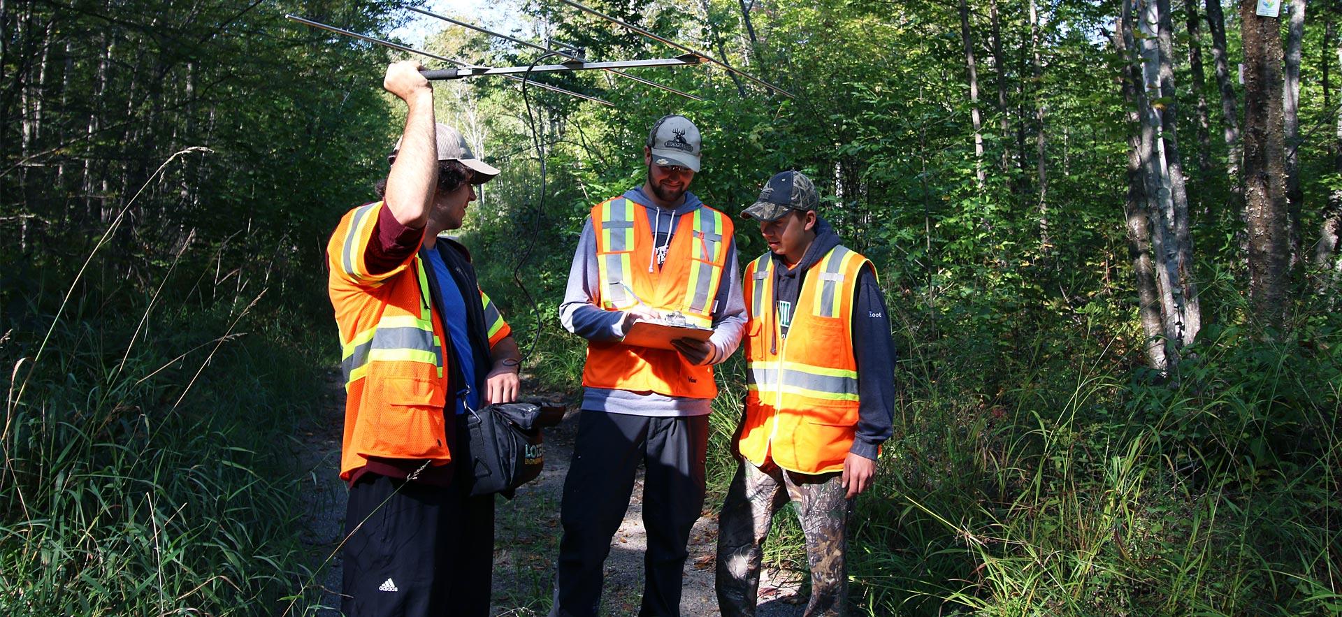 Three male forestry conservation students set up communication.