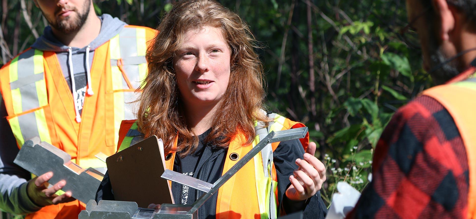 A female forestry conservation student checks her specimen trap.