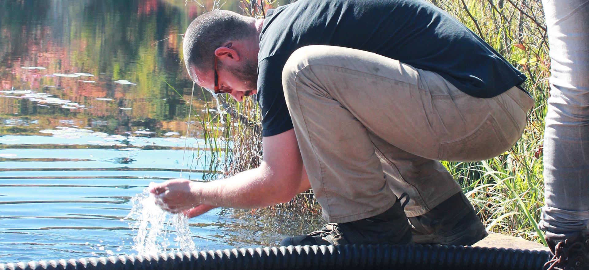 Male forestry conservation technician student cools off near river.