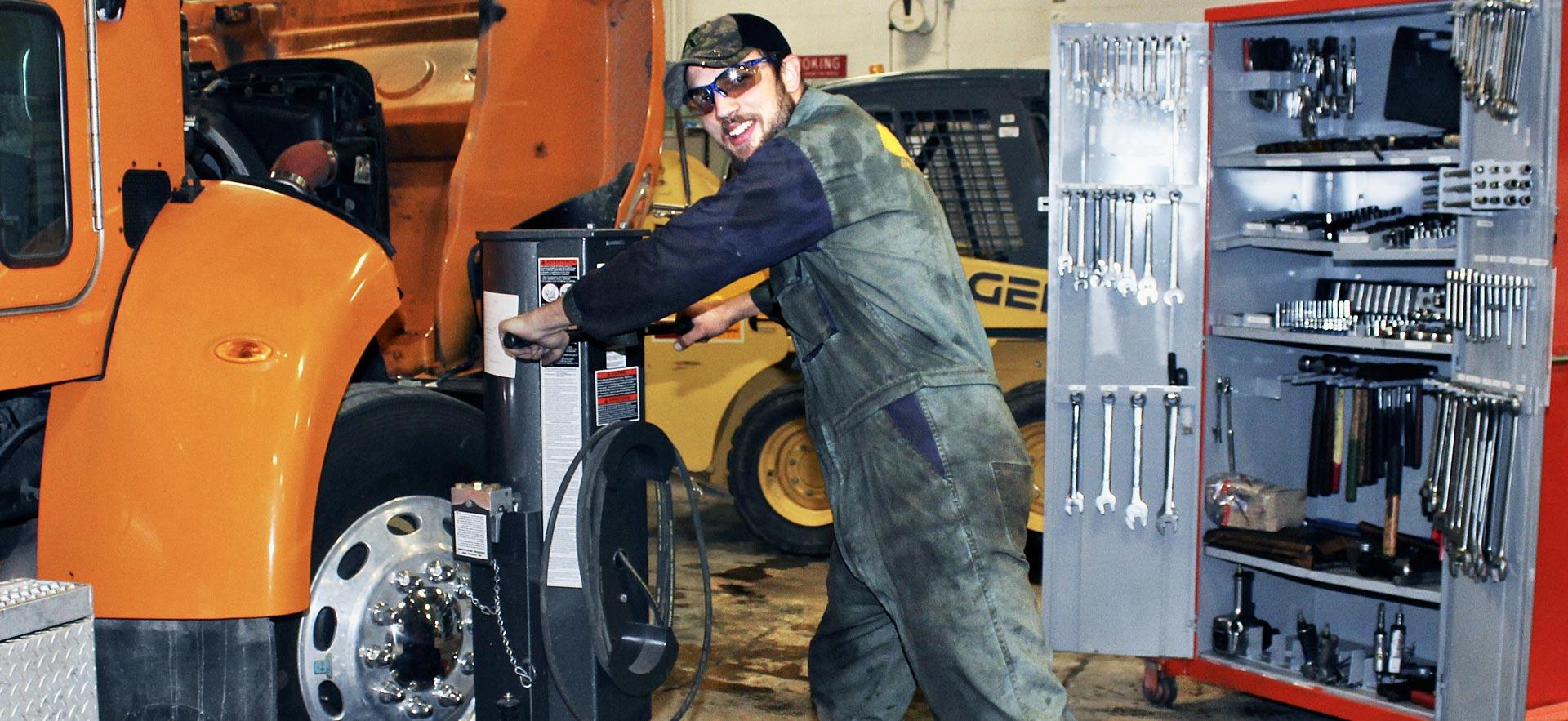 One male heavy equipment student work on a truck.