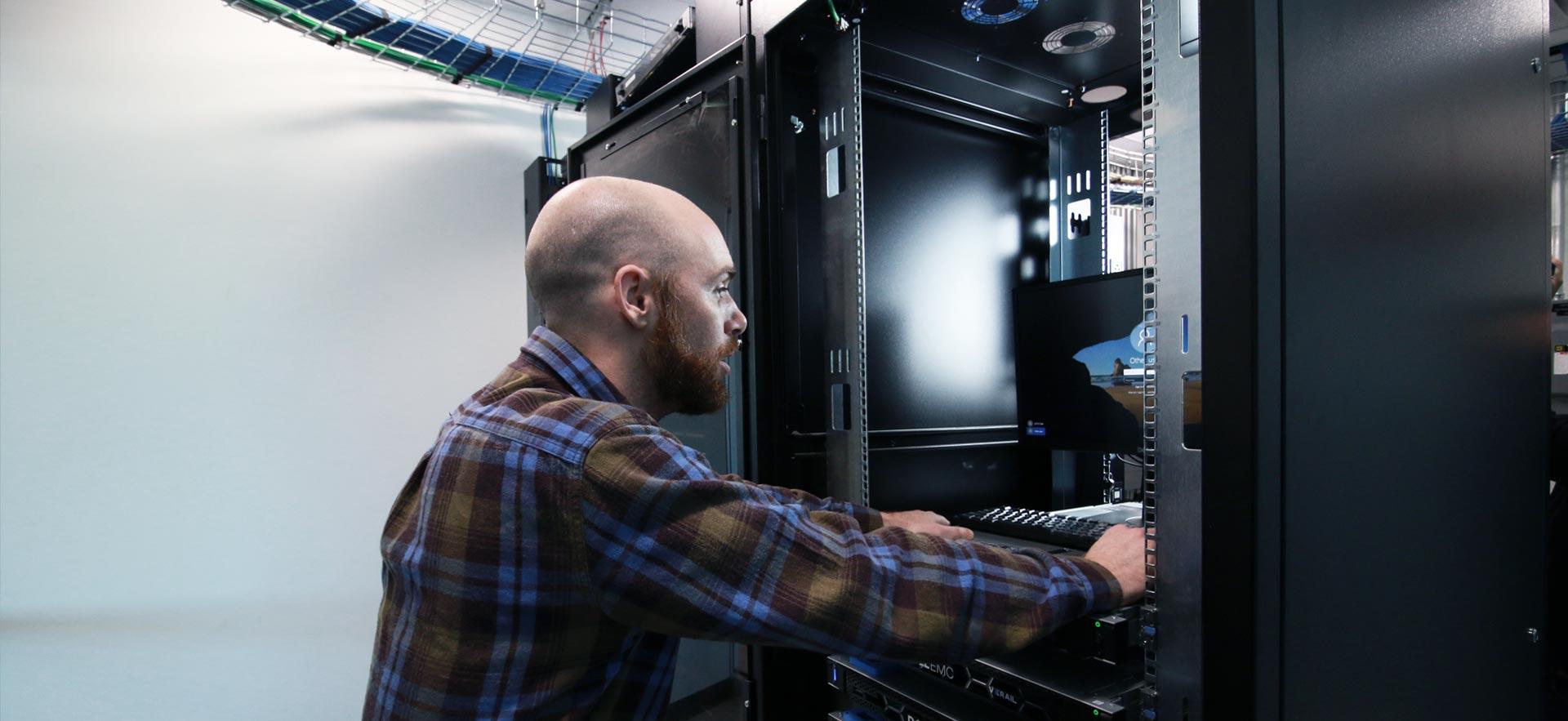 Male computer technician reviews a Sault College computer server.