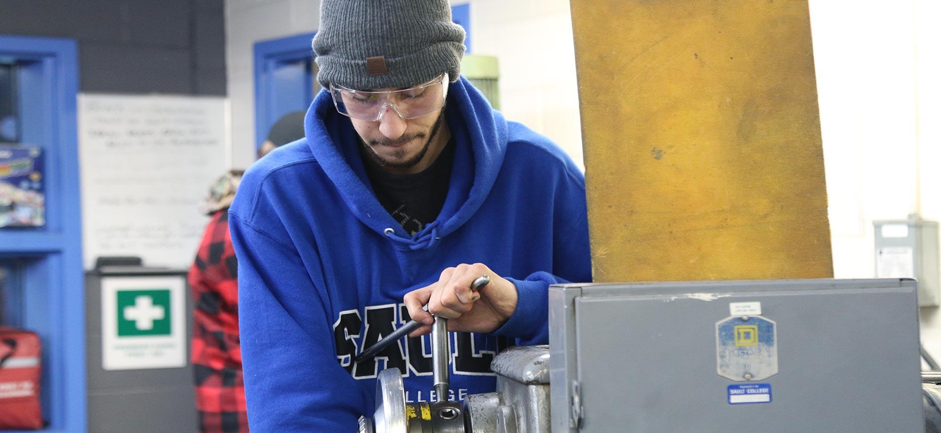 One male machine shop student working on a class project.