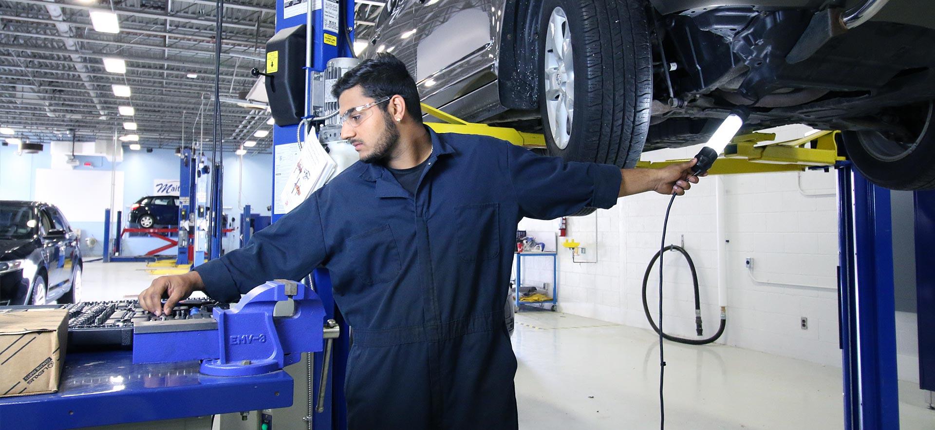 A male Motive Power Fundamentals - Automotive Repair student works on an engine.