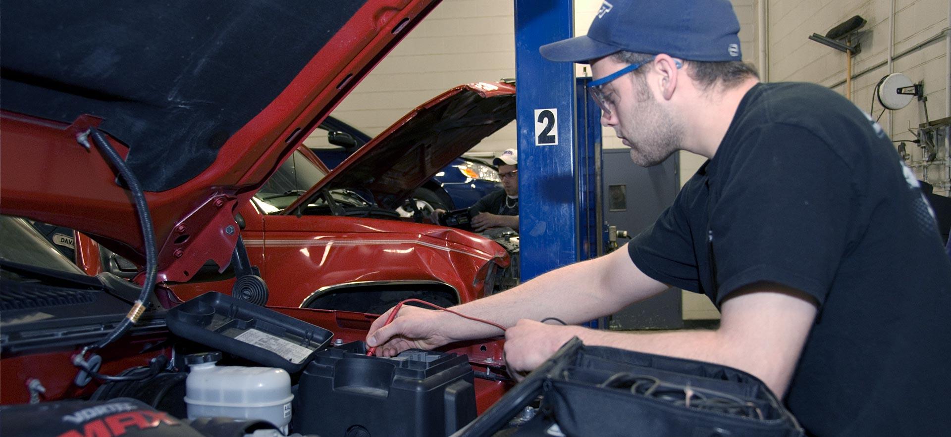 A male Motive Power Fundamentals - Automotive Repair student works on an engine.