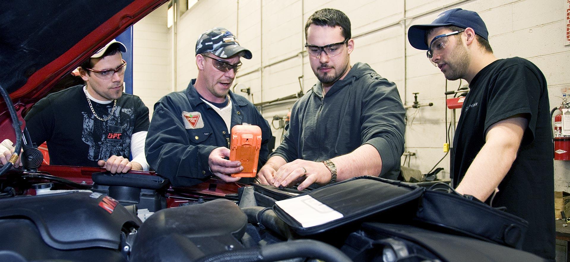 Four male Motive Power Fundamentals - Automotive Repair students works on an engine.