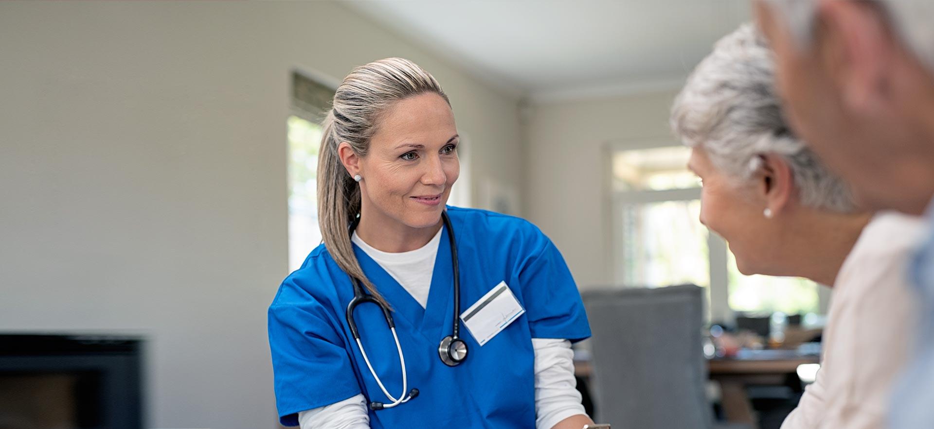 Female nurse treating elderly couple.