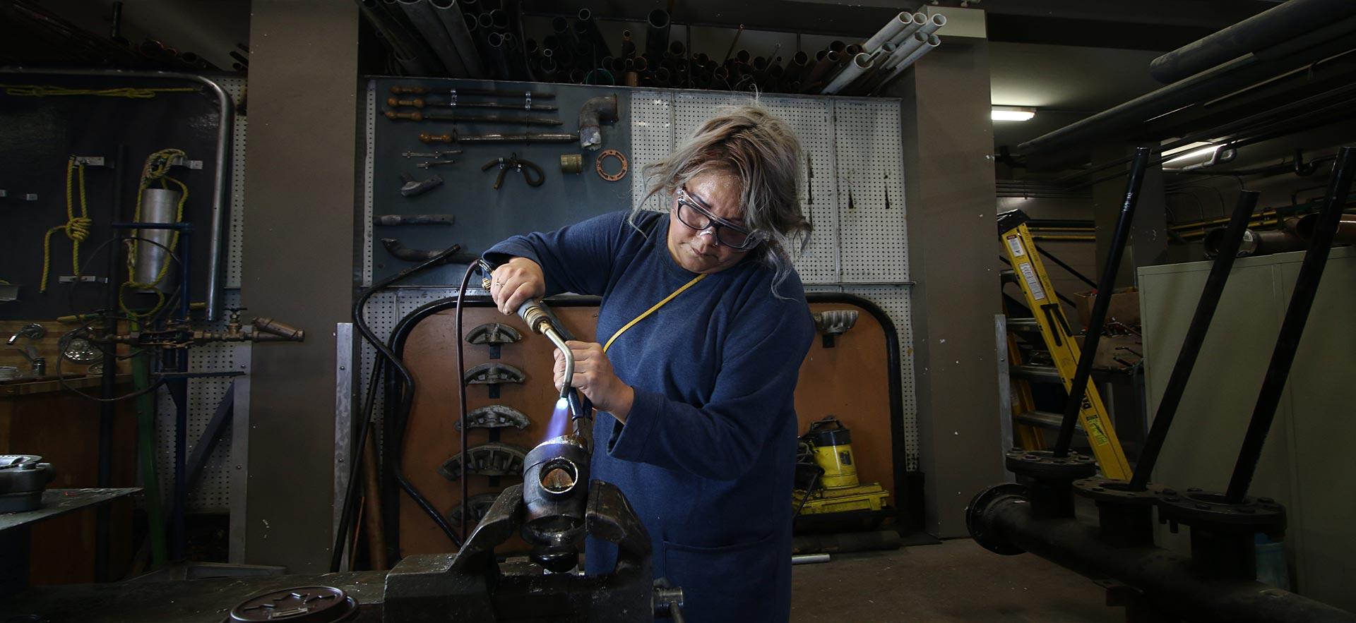 One female Pre-Trades and Technology student works on metal fabrication.