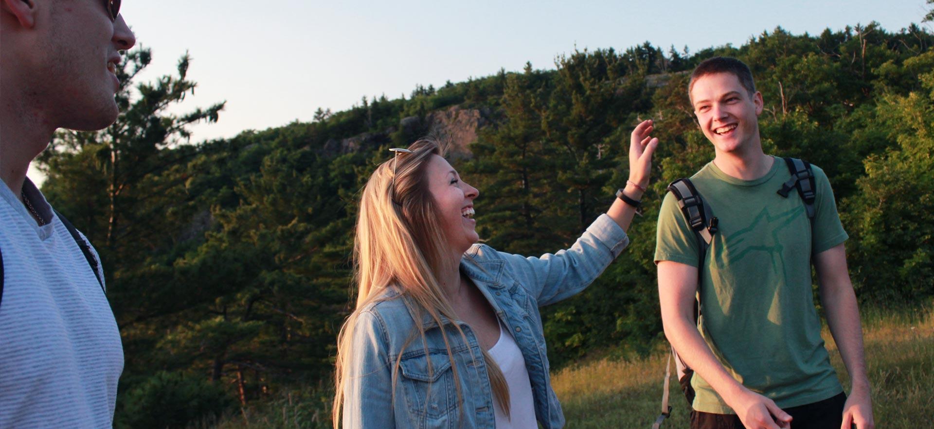 Three young friends hiking and smiling.