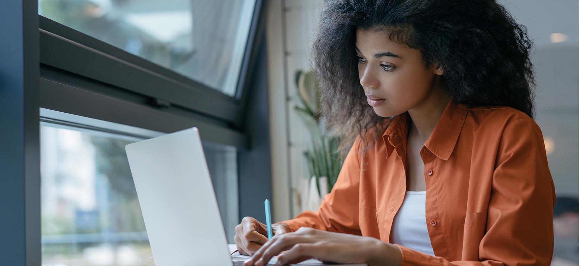 Young woman on a computer near a window.