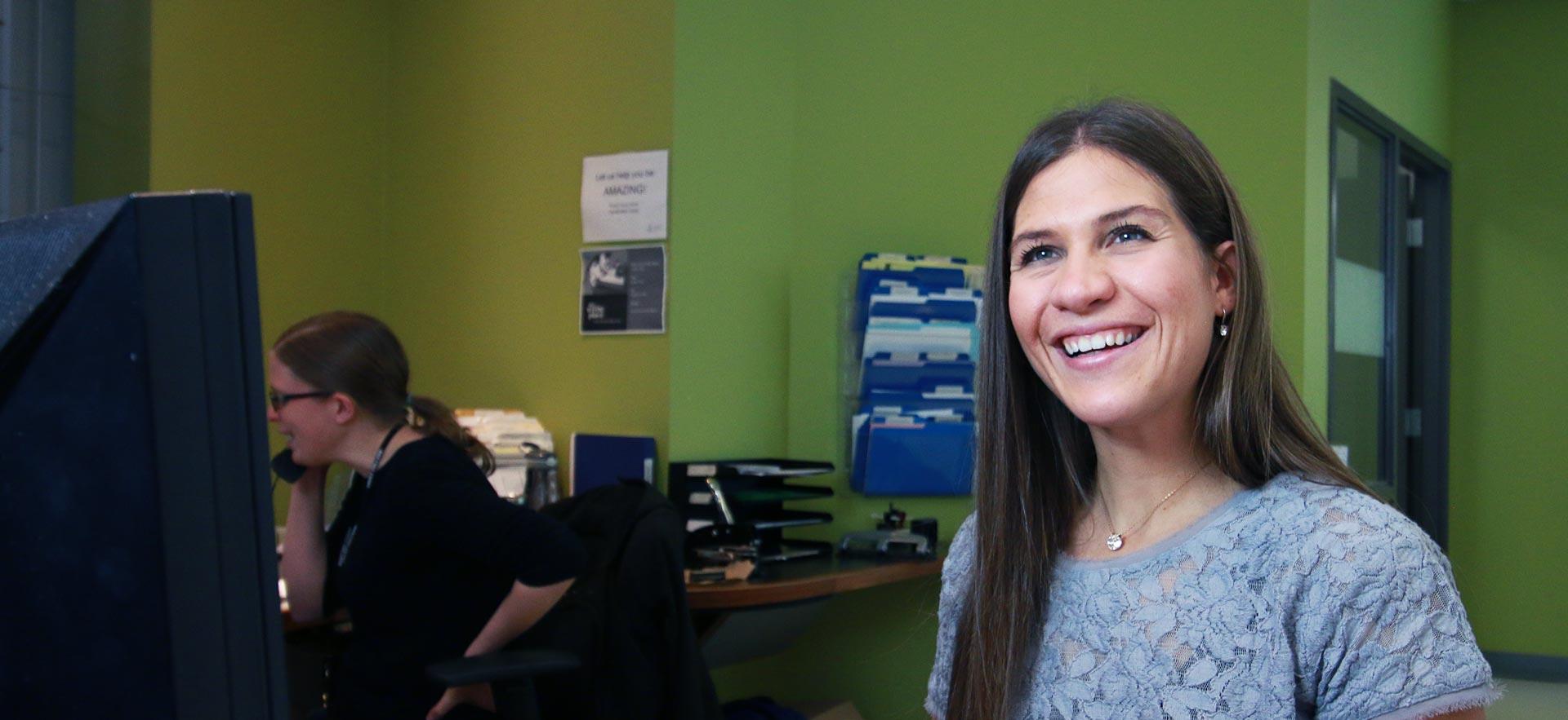 Young woman smiling and working in the Registrar's Office.