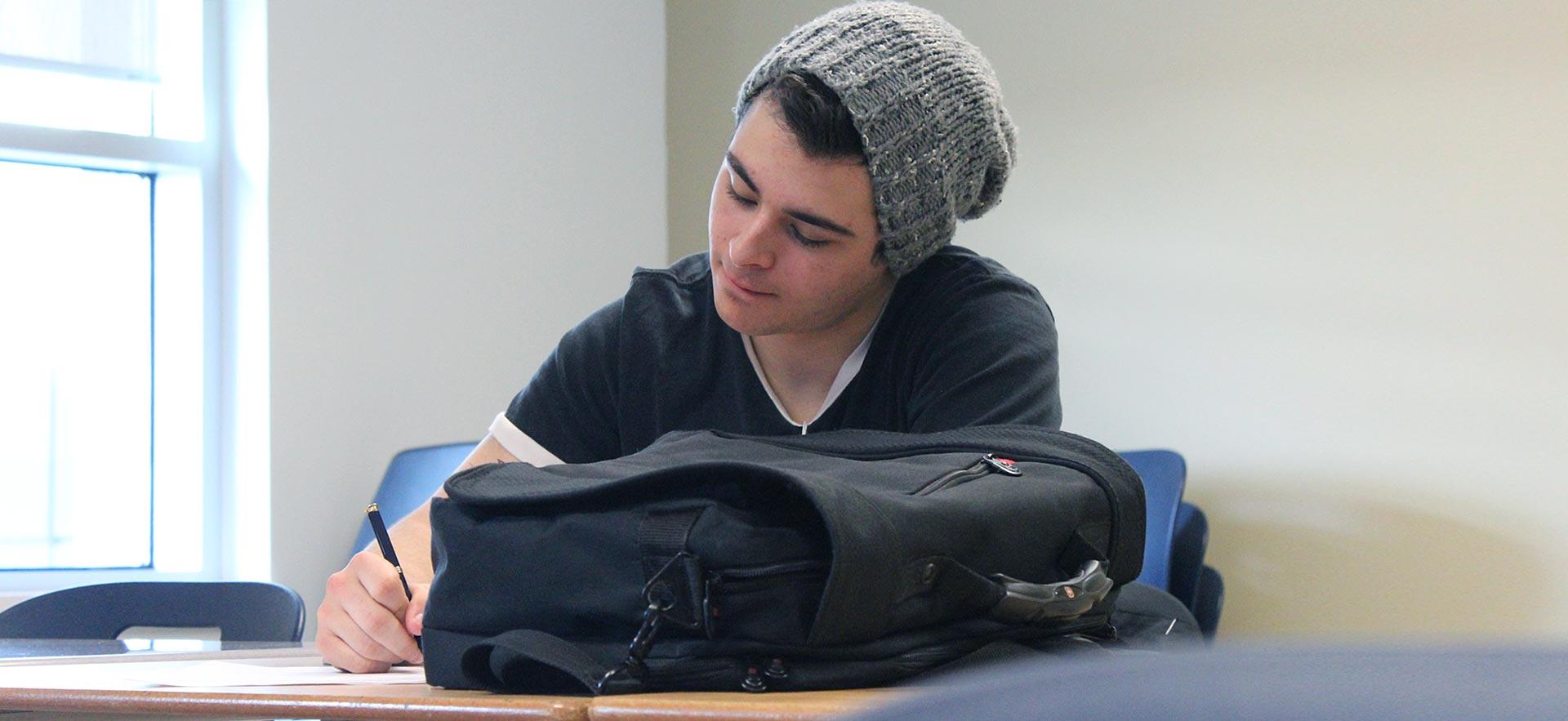 Male student taking notes in class.