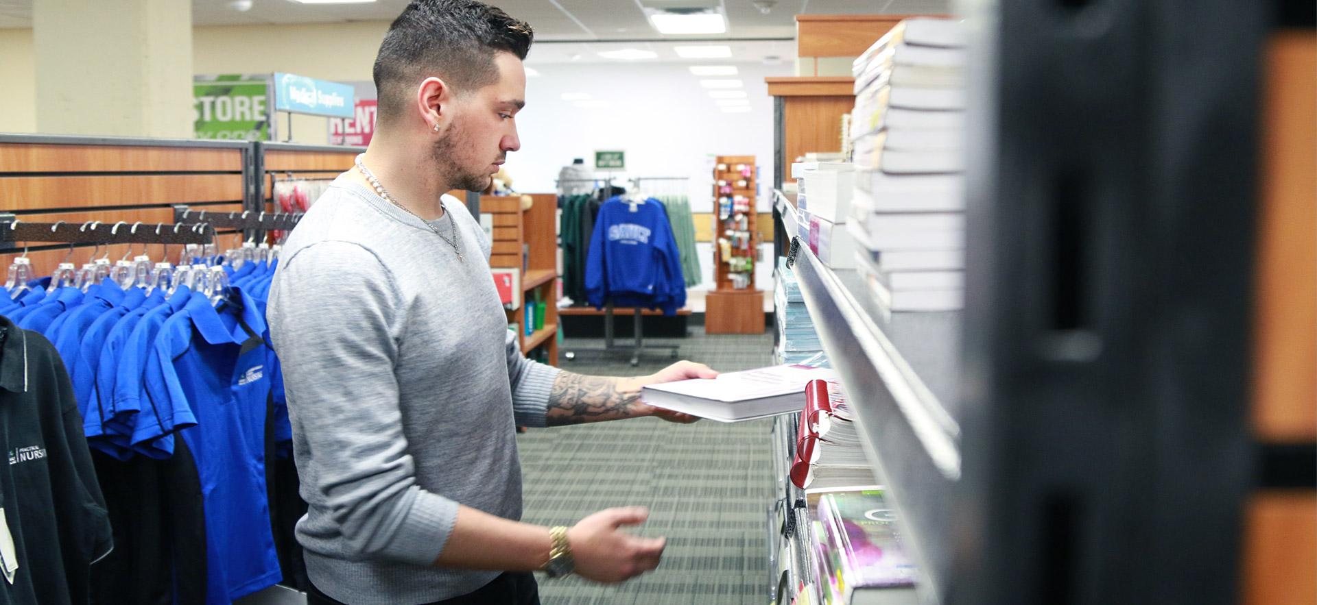 Male student reviewing a book in the book store.
