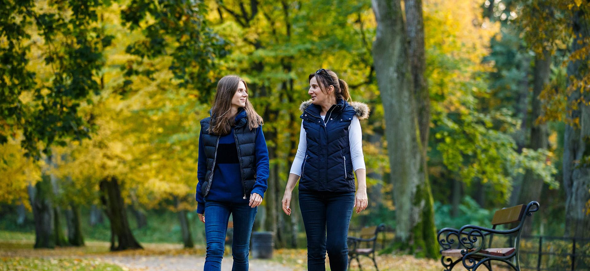 Two young women walking in park.