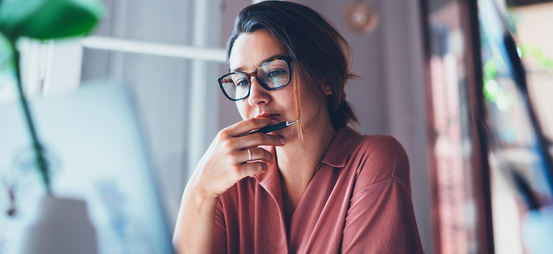 Female student thinking at her computer.