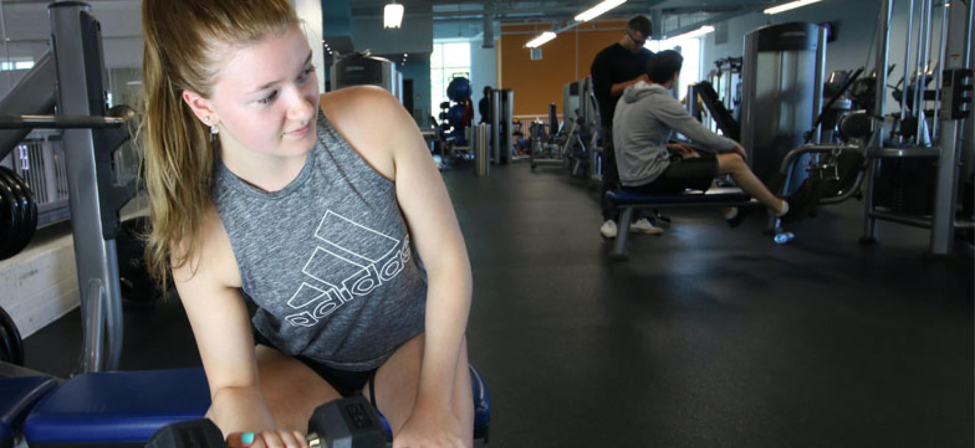 Girl lifting weights in health and wellness area